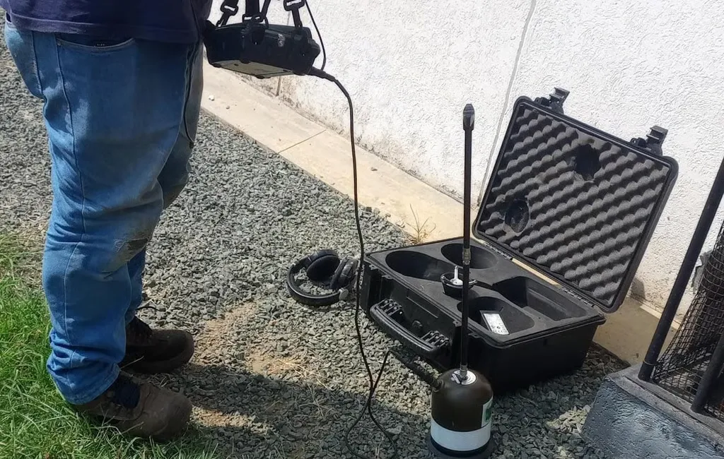 Técnico junto al maletín del geófono, con el sensor apoyado en el suelo al pie de un muro