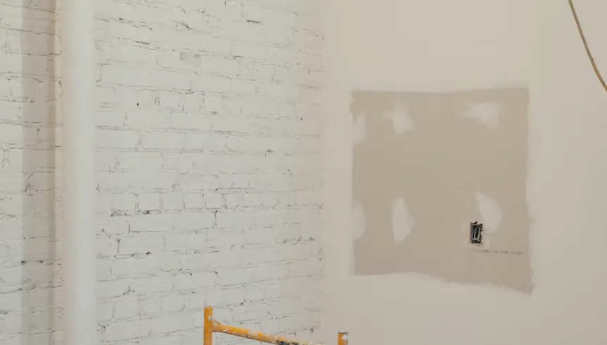 Pared de ladrillo pintada de blanco junto a un muro con el estuco aplicado